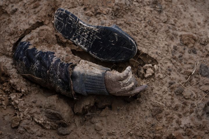 The hand of a corpse emerges from a mass grave in Bucha.