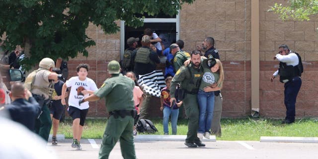 Children run to safety after escaping through a window during a mass shooting at Robb Elementary School in Uvalde, Texas, May 24, 2022.
